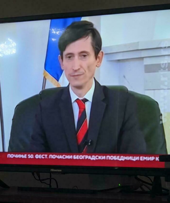 Man in suit on TV screen with flag behind him, part of misleading and confusing photos that seem like a glitch in real life