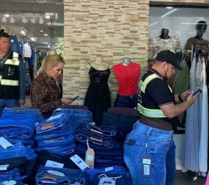 Two people standing behind stacked jeans with a mannequin wearing jeans creating a misleading photo glitch effect.