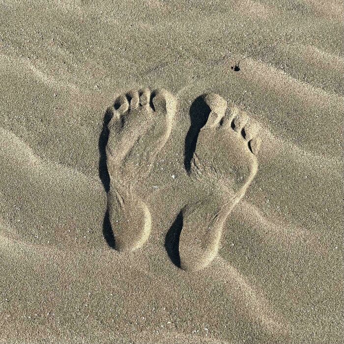 Footprints in sand showing toes but appearing sculpted, a misleading and confusing photo that seems like a glitch in real life.