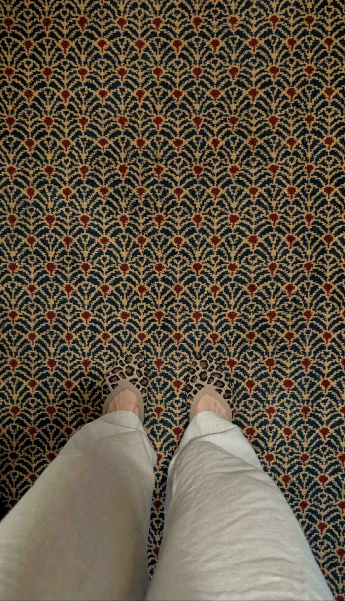 Person wearing leopard print shoes standing on a patterned carpet creating a misleading and confusing visual glitch effect.