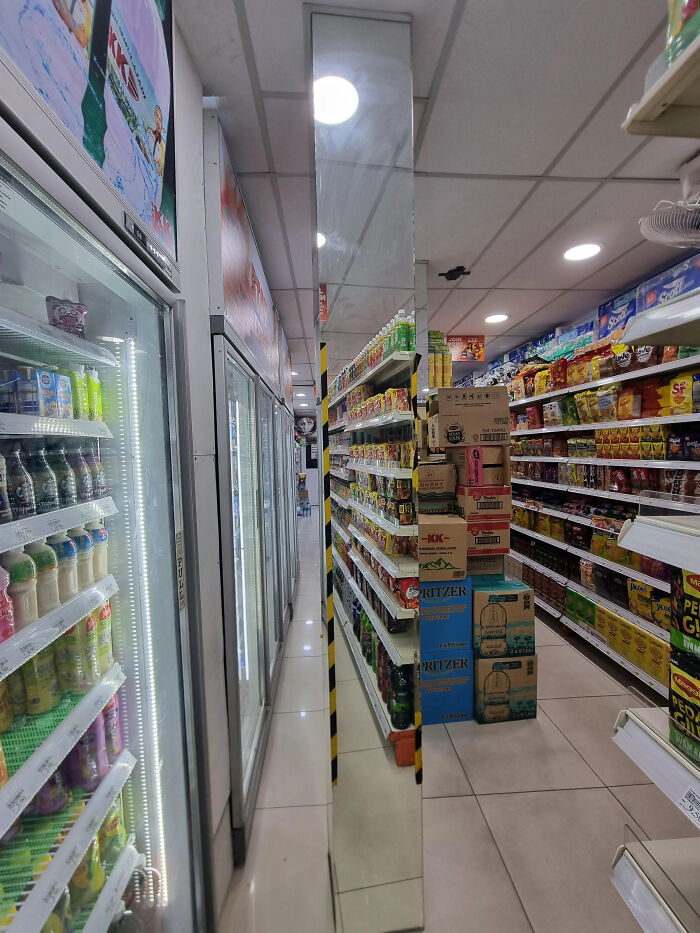 Grocery store aisle with a mirrored pillar creating a confusing photo that seems like a glitch in real life.