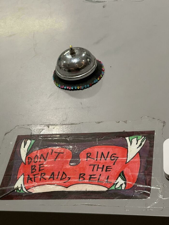 Reception bell with a colorful sign that humorously says dont be afraid ring the bell, a funny sign fail.