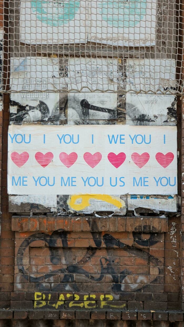 Faded and torn sign with hearts and text on a brick wall, showing signs that went wrong and turned comedic.