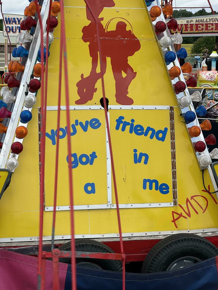 Yellow carnival sign with the phrase youve friend got in a me, a funny sign that went wrong at an amusement park.
