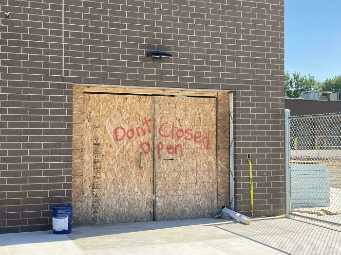 Boarded-up doorway with graffiti reading Dont Closed Open, an example of signs that went wrong and turned into comedic gold.