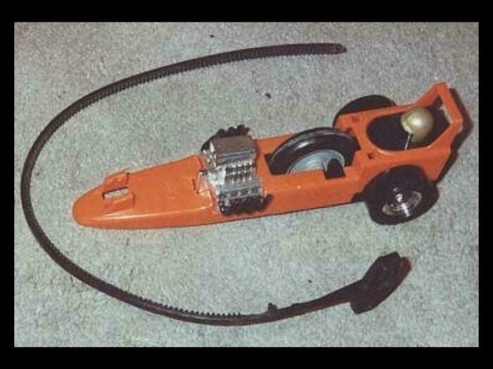 Orange toy race car with a long, flexible black track, evoking images that take you way back to childhood fun.