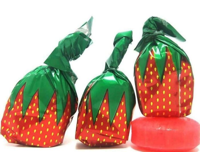 Three strawberry-shaped hard candies in wrappers, a treat that might take you way back.
