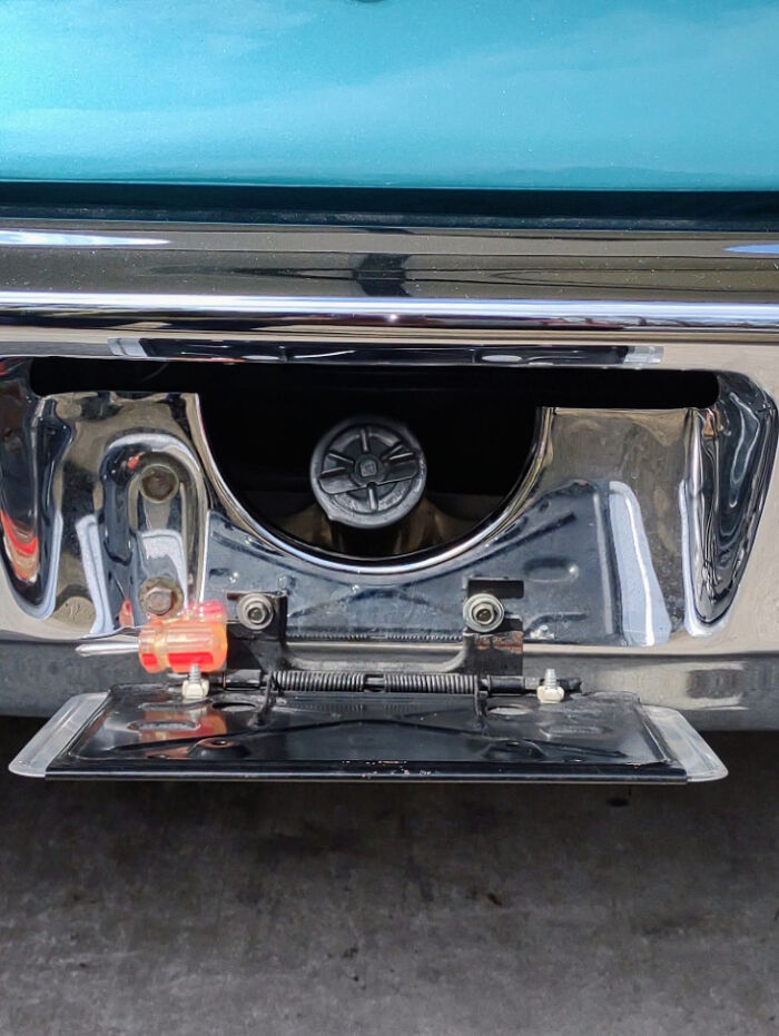 An old car gas cap hidden behind a flip-down license plate, reminding you how old you are.