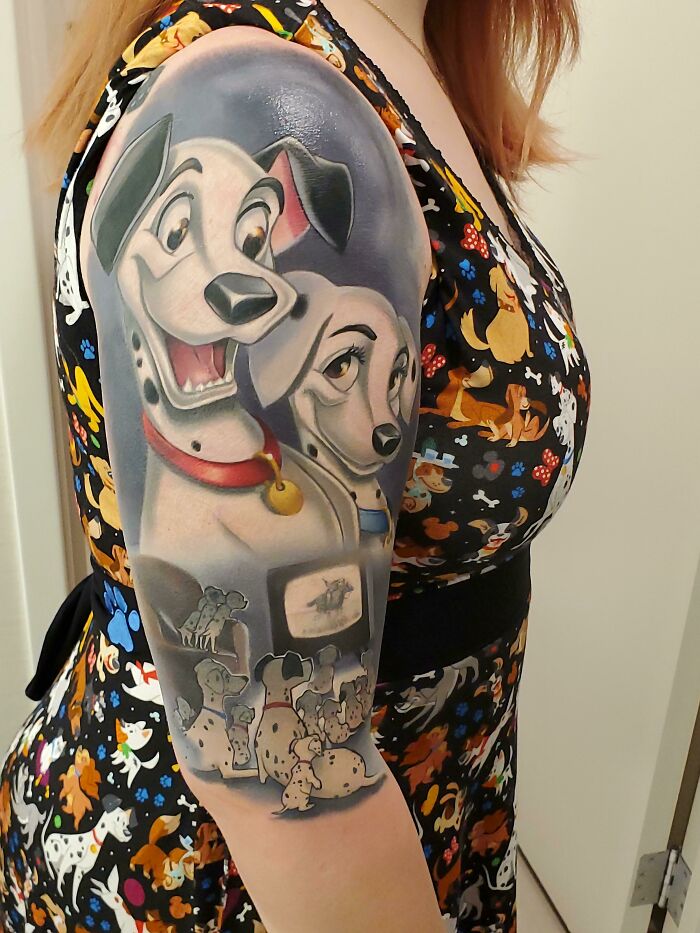 Colorful cool tattoo of animated Dalmatian dogs on a woman’s upper arm, showcasing detailed and vibrant design.