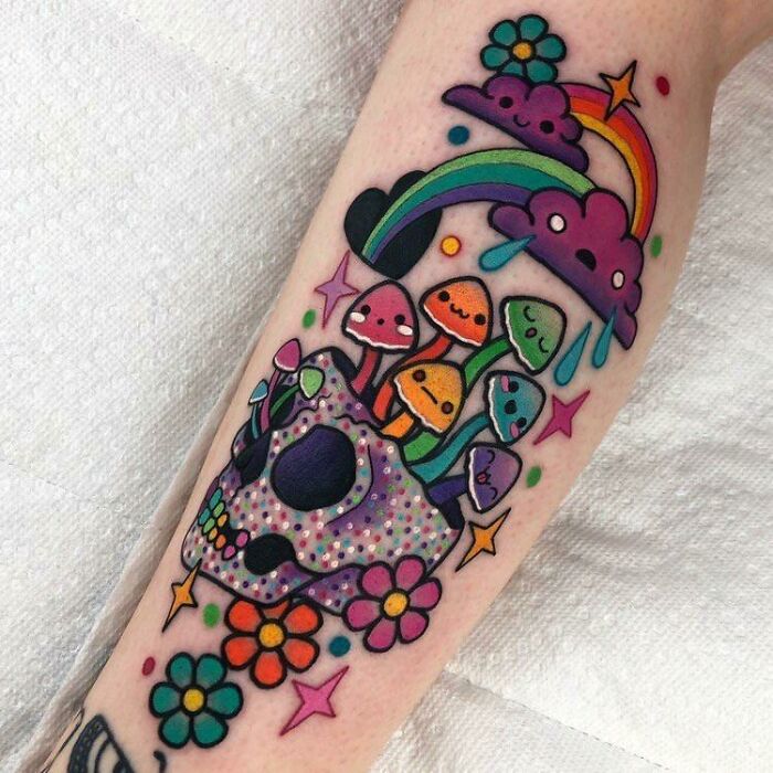 Colorful skull tattoo with mushrooms, flowers, and rainbow clouds illustrating cool tattoos with no regrets.