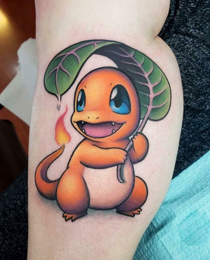 Colorful Charmander tattoo holding a leaf on inner arm showcasing cool tattoos and vibrant body art design.