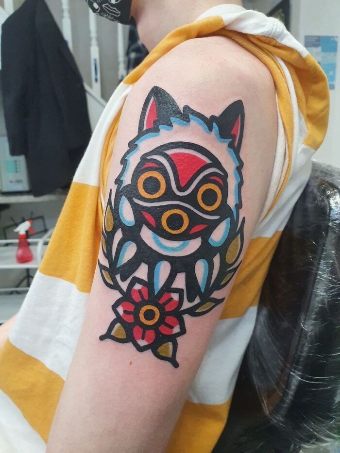 Colorful cool tattoo on upper arm depicting a stylized animal face with bold lines and a flower, showcasing unique cool tattoos.