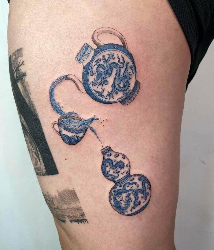 Blue dragon-themed cool tattoo of a teapot pouring into a cup and another vessel on the thigh, showcasing cool tattoos design.