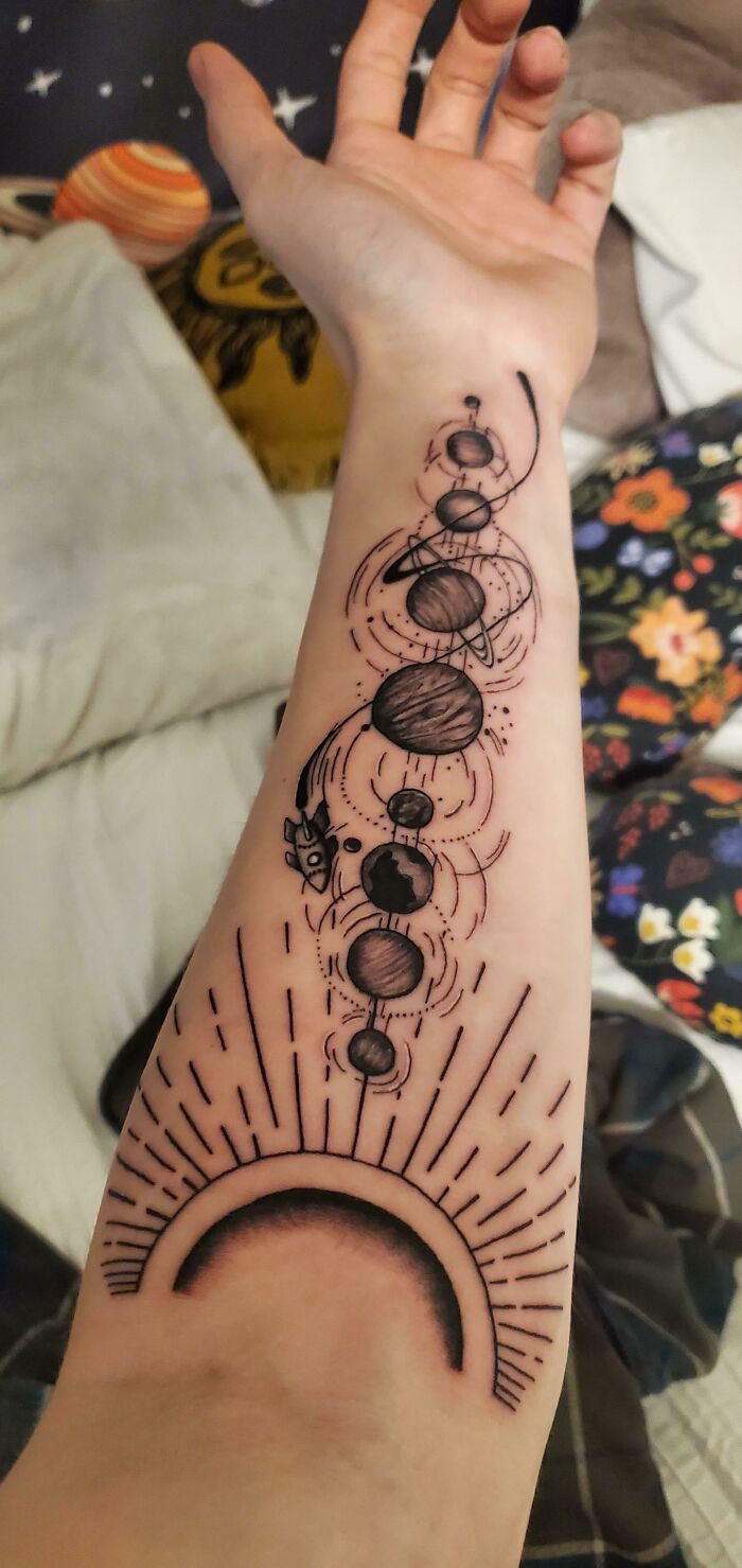 Forearm tattoo of solar system planets with sun and rocket design, showcasing cool tattoos without regrets.