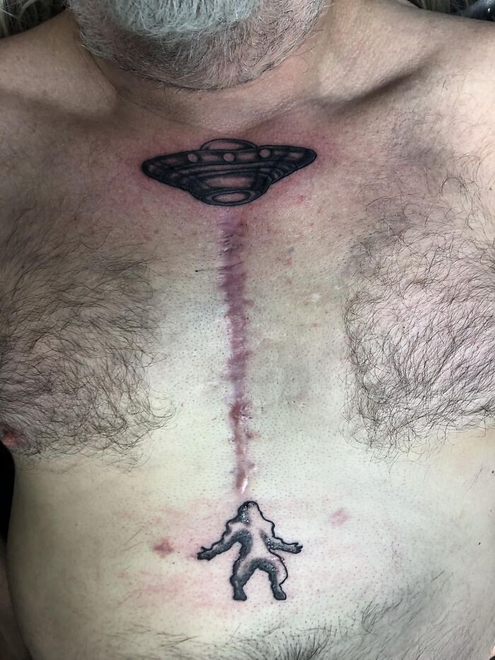 Chest tattoos of a UFO and Bigfoot positioned on either side of a long scar, showcasing cool tattoos without regrets.