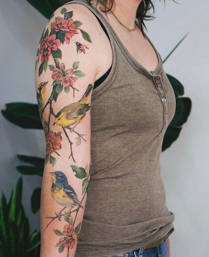 Colorful floral and bird tattoos on a woman's arm showcasing cool tattoos without permanent regrets.