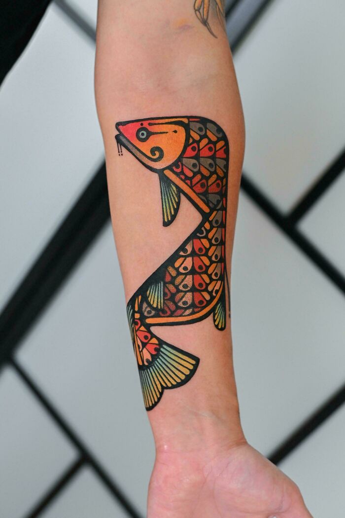 Colorful koi fish tattoo on inner forearm, featuring detailed scales and bold black outlines, a cool tattoo design.