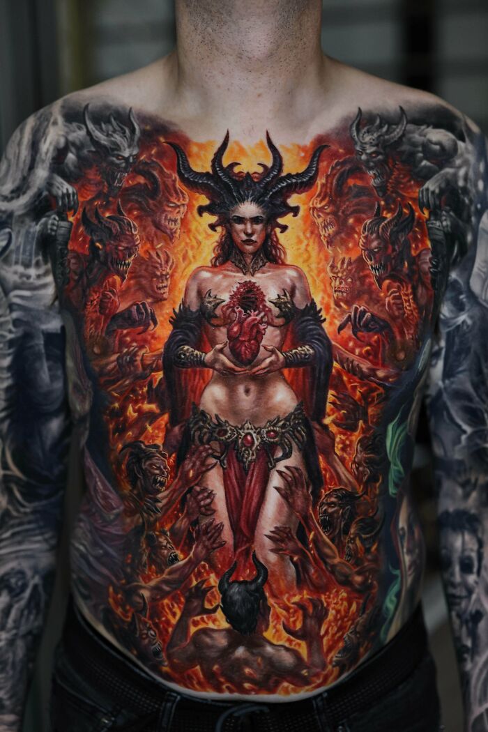 Full chest tattoo of a horned woman holding a heart surrounded by fiery demons and intricate dark designs, cool tattoos inspiration.