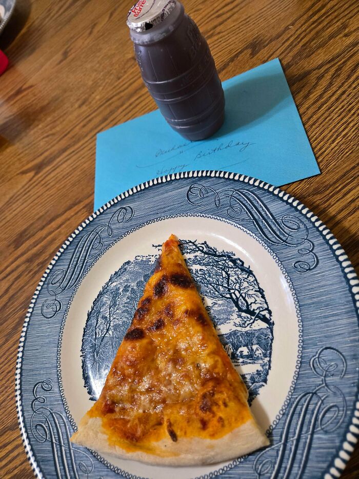 Slice of cheese pizza on a vintage plate with a nostalgic chocolate milk bottle and handwritten note on wooden table.