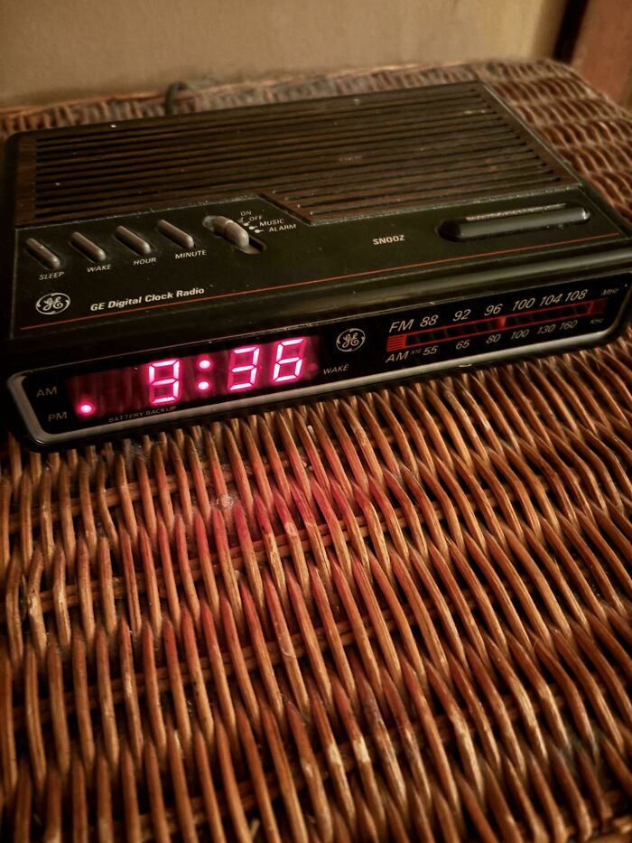 Vintage GE digital clock radio showing 8:36 on red LED display, placed on a woven wicker surface, nostalgic Gen X item.