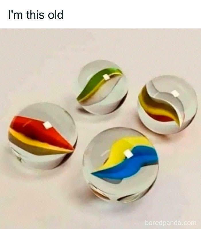 Four vintage glass marbles with colorful swirls, illustrating nostalgic and relatable Gen X childhood toys.