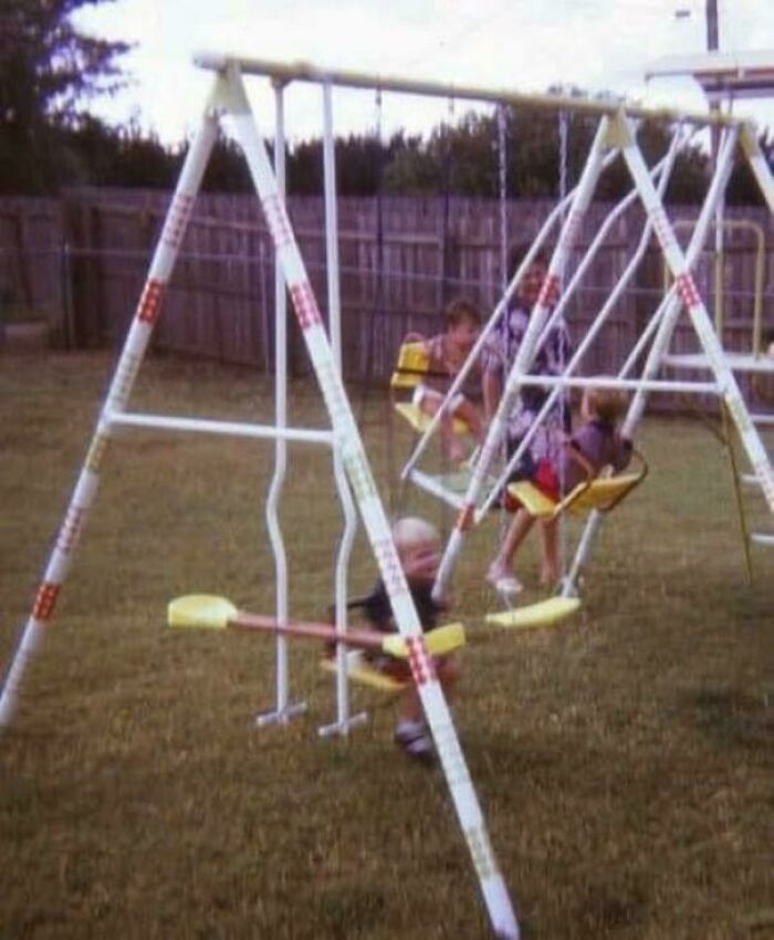 Kids playing on a vintage backyard swing set, evoking nostalgic and relatable memories for Gen X.