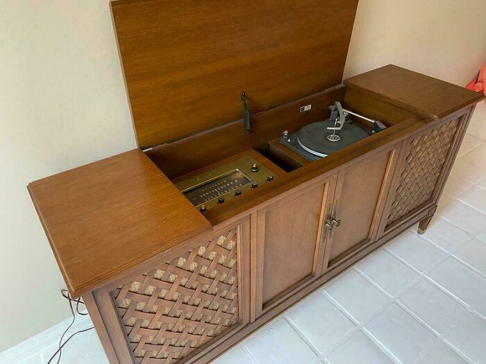 Vintage wooden record player console with radio and turntable, evoking nostalgic and relatable Gen X memories.