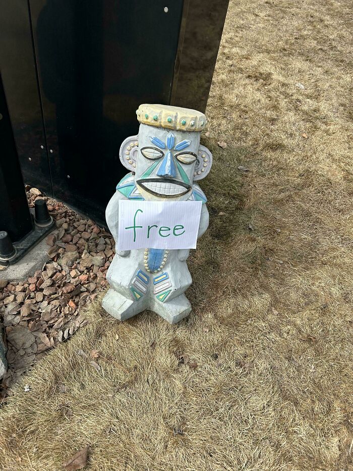 Decorative stone statue with a free sign, evoking nostalgic and relatable Gen X memories outdoors on dry grass.