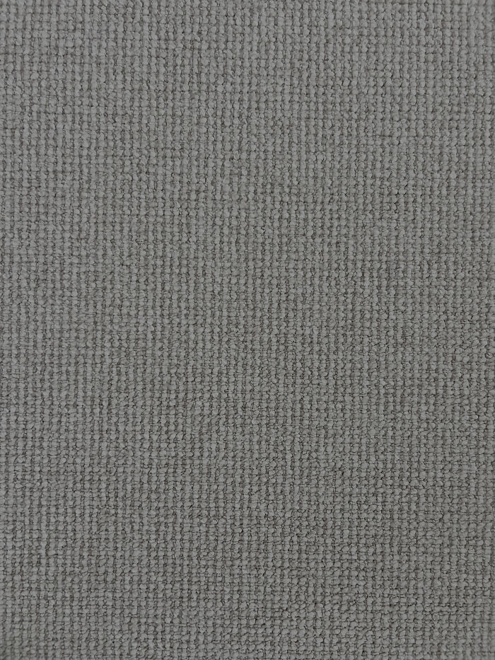 Gray textured fabric close-up with a perfectly camouflaged object blending into the pattern, hard to find at first glance.