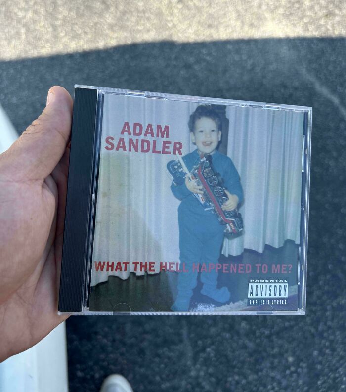 Hand holding Adam Sandler CD album cover featuring a childhood photo and nostalgic ’90s memories.