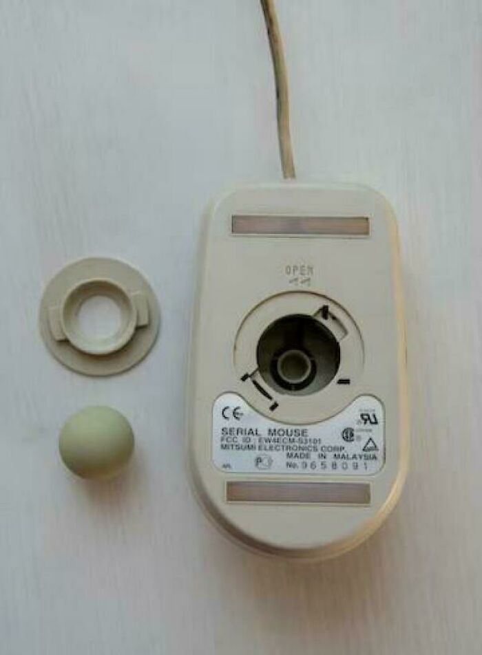 Bottom view of a vintage 1990s computer serial ball mouse with ball and casing removed for cleaning.