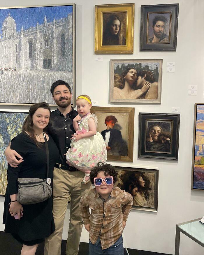 Family posing happily in front of art gallery paintings