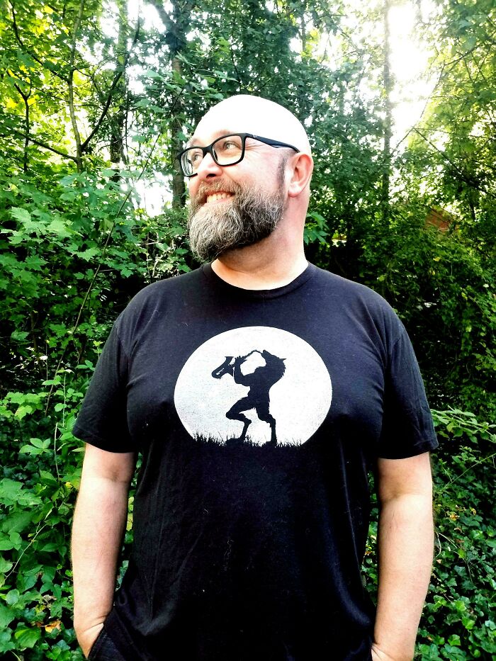Smiling bearded man wearing a black t-shirt with a dancing figure print outdoors