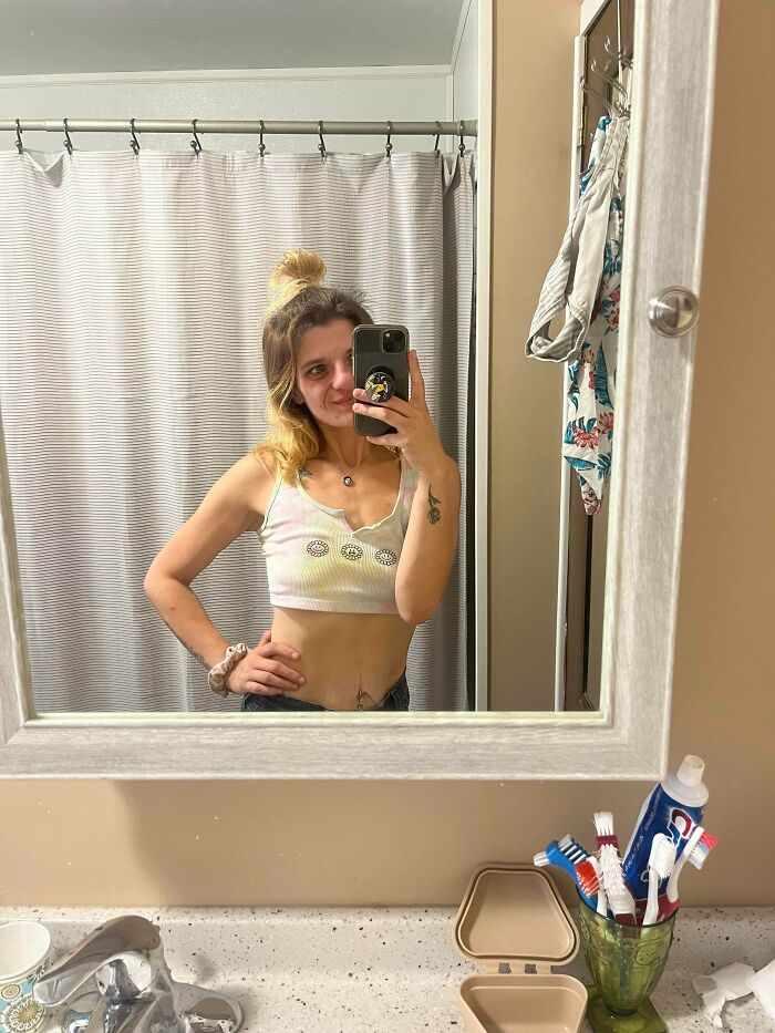 Young woman smiling taking mirror selfie in bathroom