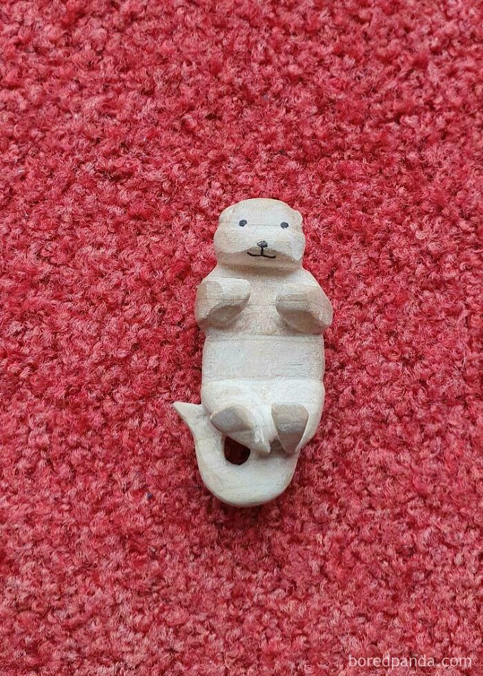 Small carved wooden otter figurine lying on a red carpet