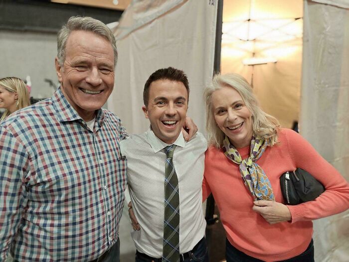 Three smiling adults posing together radiating warmth and wholesome vibes