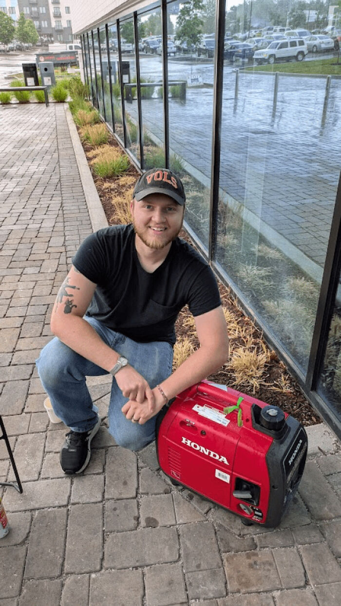 Smiling man crouched beside a red Honda generator reflecting kindness and helpfulness