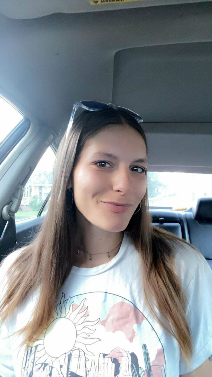 Smiling woman taking a selfie inside a car with sunglasses on head