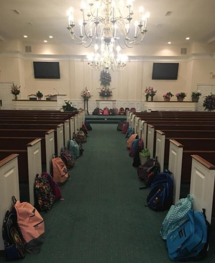 Backpacks lined up along pews in a church aisle in a wholesome setting