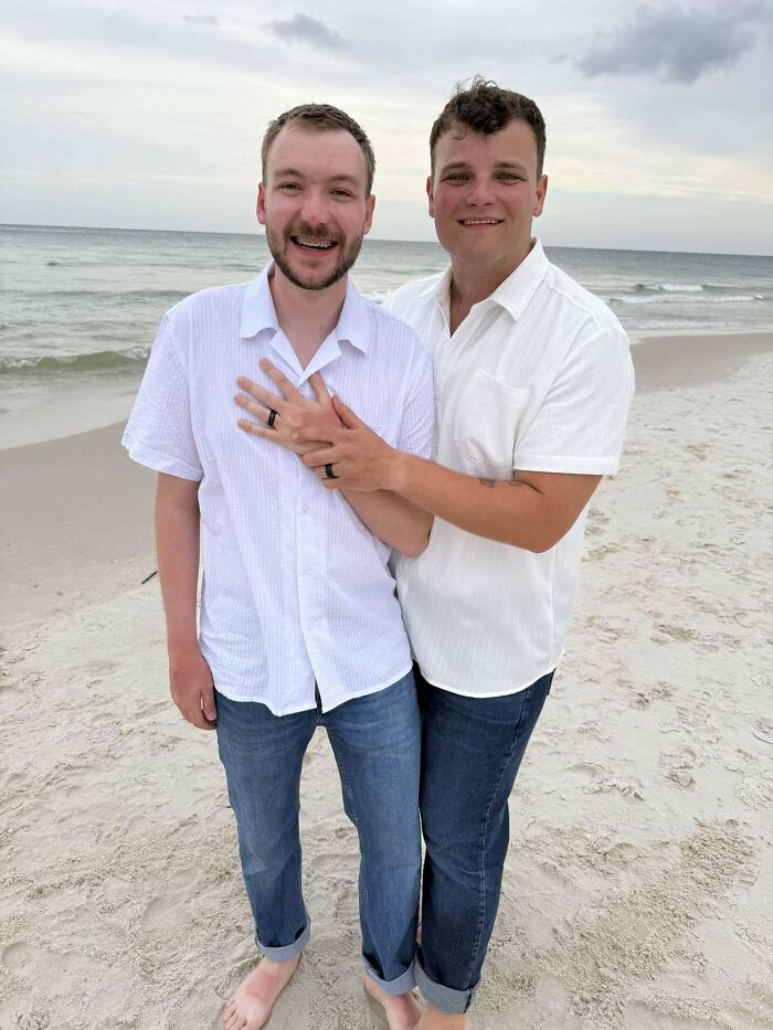 Happy couple on beach showing their wedding rings feeling warm and fuzzy