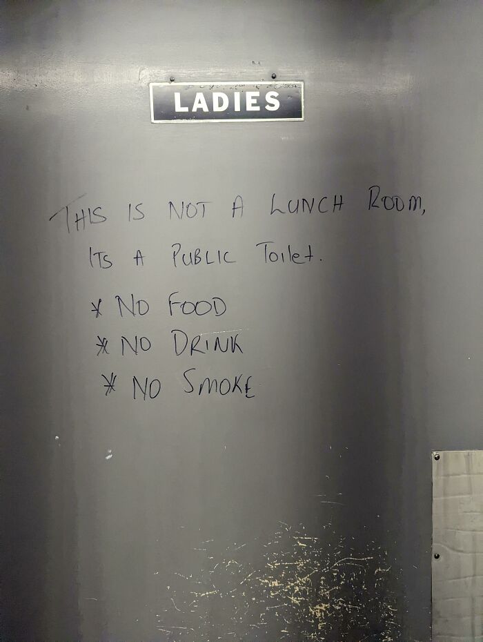 A passive-aggressive note on a public toilet door reminds users it is not a lunch room, prohibiting food, drink, and smoking.