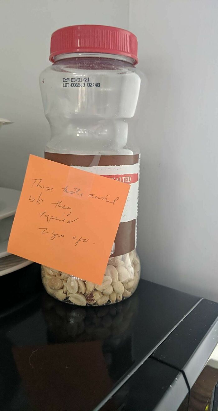 A passive-aggressive note stuck on a jar of peanuts, stating they expired two years ago.