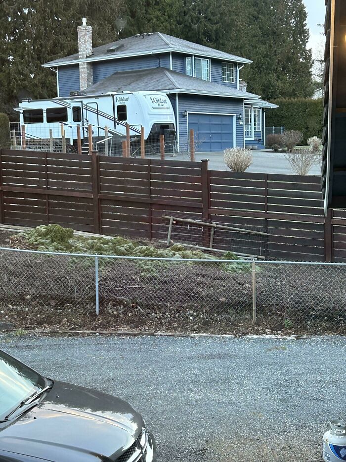 A large RV parked next to a house with a passive-aggressive note, hinting at petty neighbor disputes.