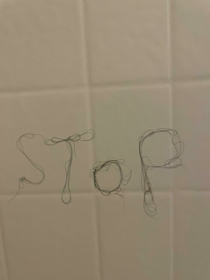 The word STOP spelled out with hair on a tile wall, a classic example of petty people and passive-aggressive notes.