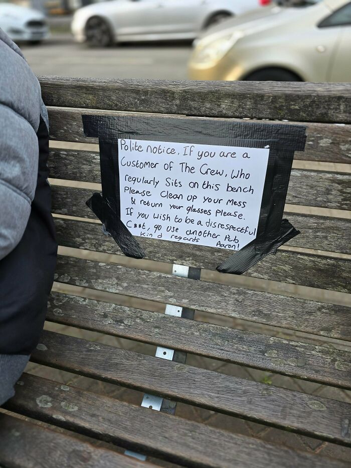 A passive-aggressive note taped to a wooden bench, warning a customer of THE CREW to clean up their mess.