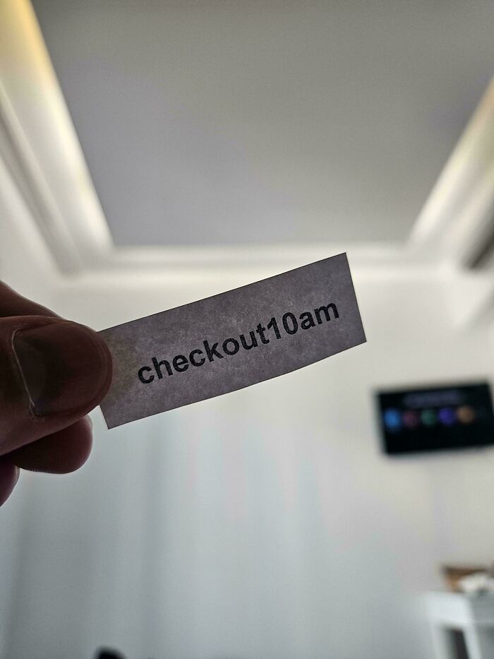 A hand holding a small piece of paper with passive-aggressive notes that says checkout10am.