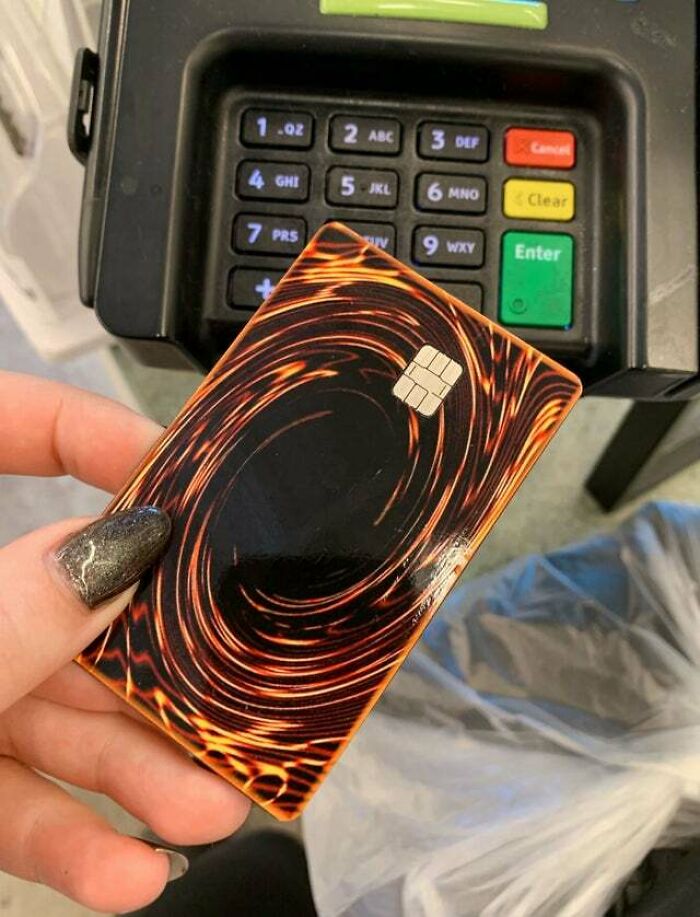Hand holding a credit card designed like a Yu-Gi-Oh card near a payment terminal in a weird and confusing image.