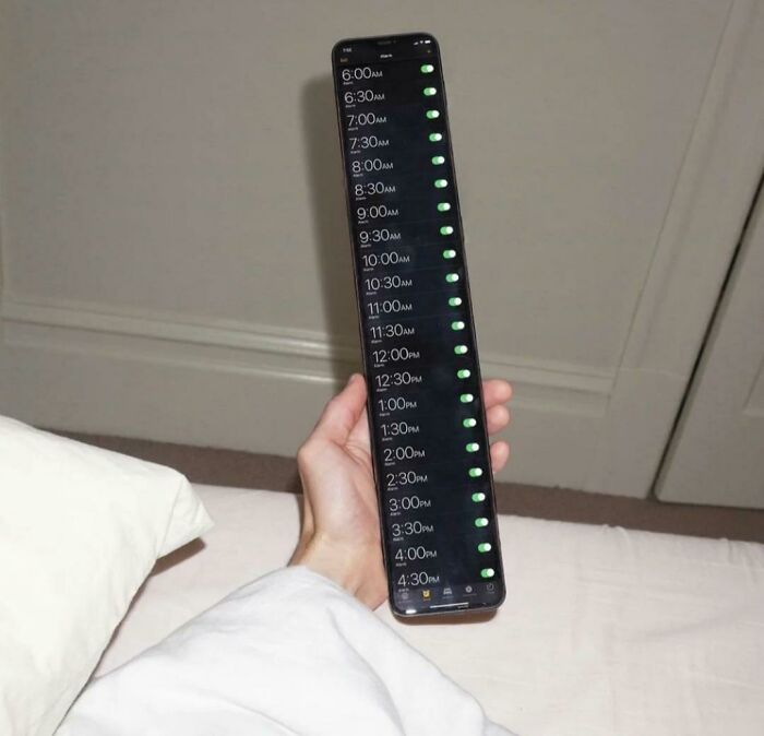 Hand holding a stretched smartphone screen showing multiple alarm times all turned on in a confusing layout.