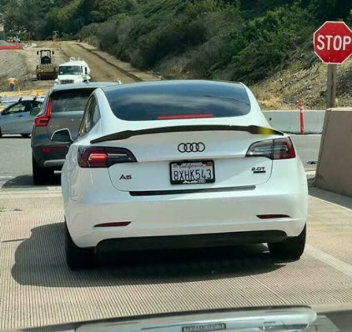White Audi A5 with a Tesla rear design caught in traffic, one of the weird and confusing cursed images you won’t unsee.