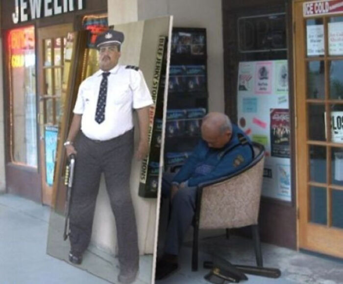 Man sitting asleep outside a shop next to a confusing optical illusion of a security guard cutout standing on the sidewalk.